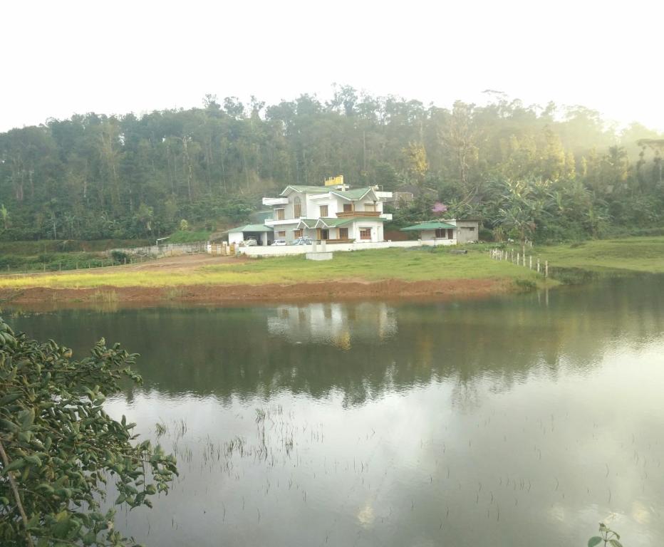 a house on a hill next to a body of water at Creekside Cabin in Madikeri