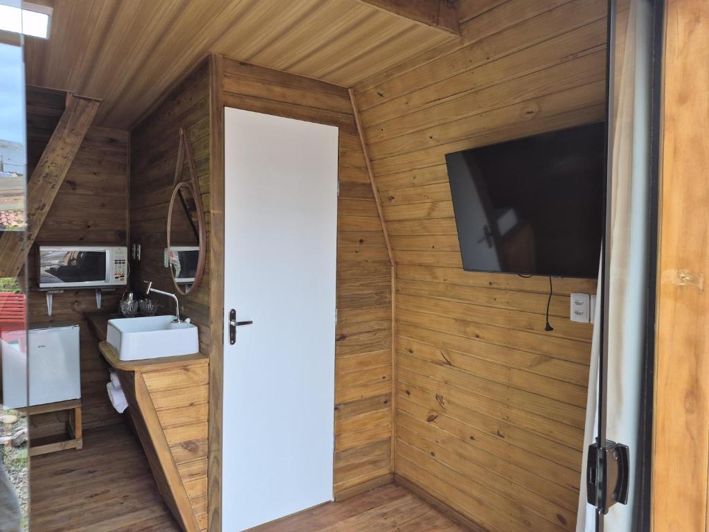 a door to a bathroom with a tv on a wall at Chalé solmar in Penha