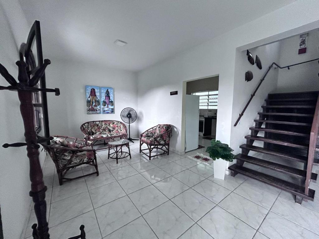 a living room with two chairs and a staircase at Casa espaçosa 100m da praia in Ubatuba