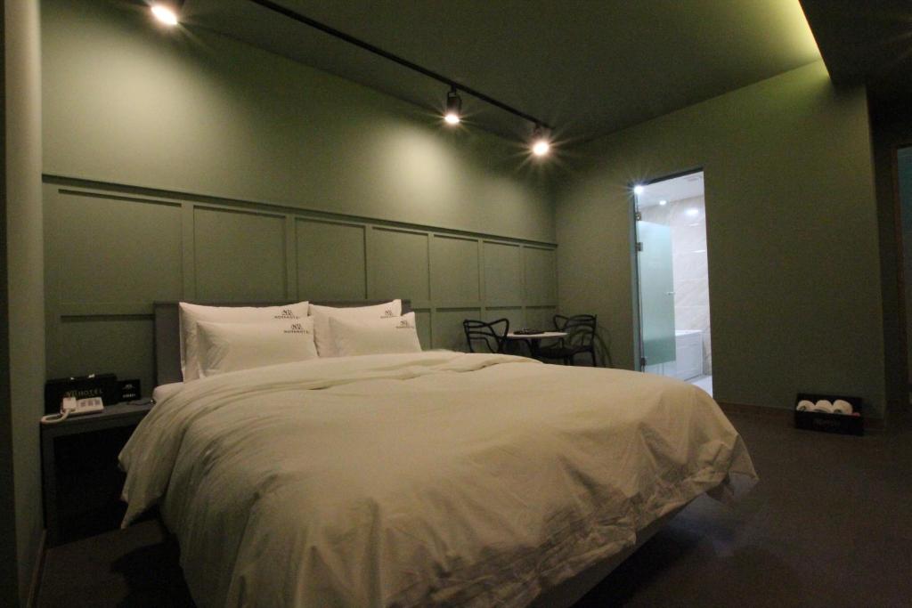 a bedroom with a large white bed and a table at Novahotel in Samgong