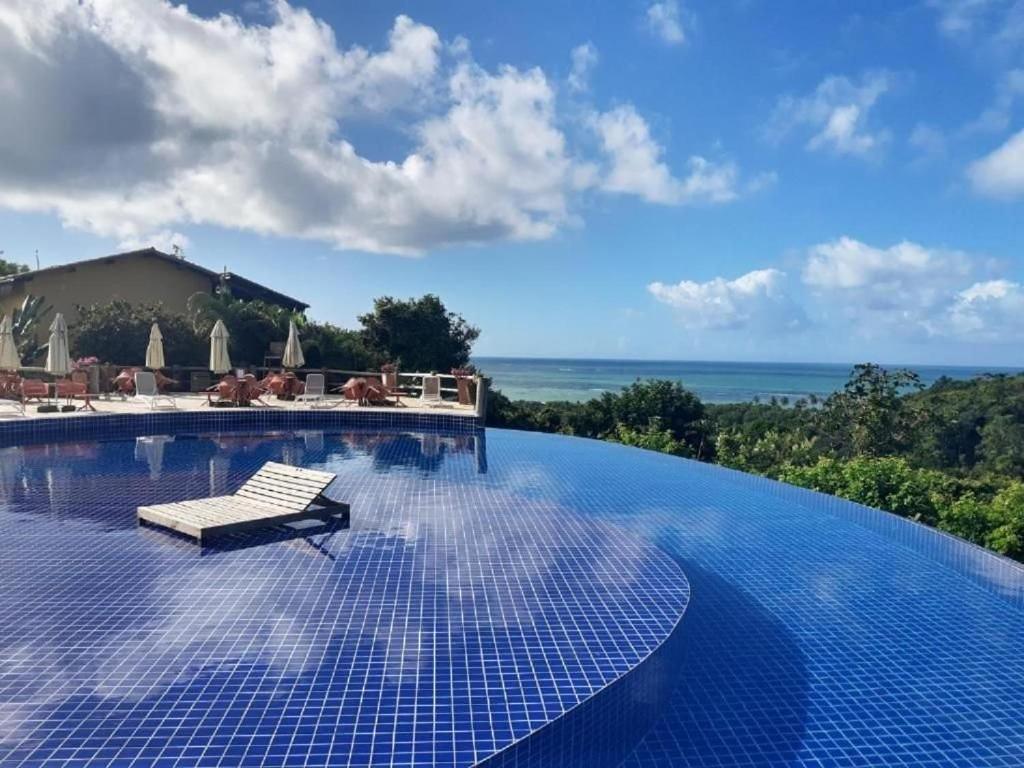 a swimming pool with a lounge chair on top of it at Flat Villas do Pratagy: Tranquilidade e Natureza ao Norte de Maceió in Maceió