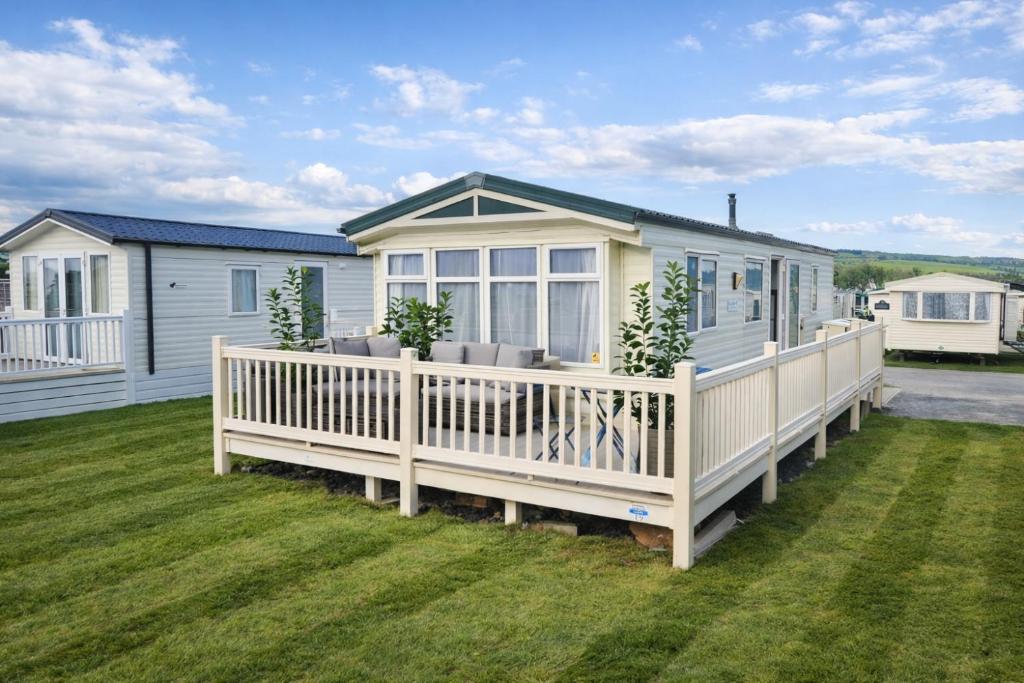 a manufactured home with a large deck and a house at Clwyd 6 in Borth