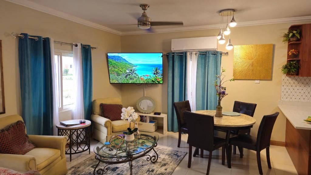 a living room with a table and a tv on the wall at The Full Maison at Ocho Rios in Ocho Rios