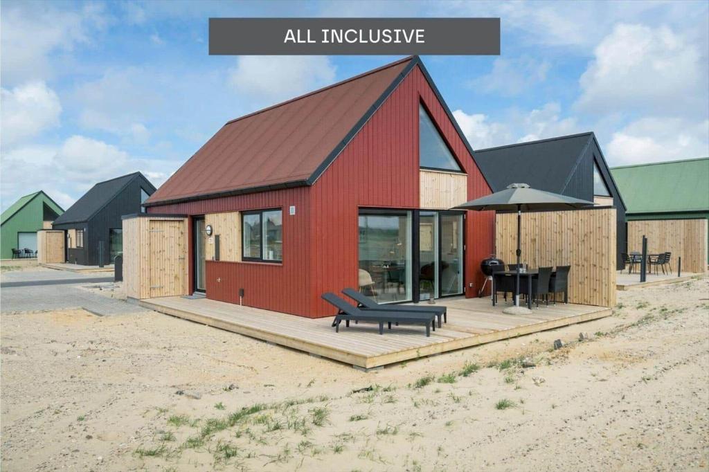 a red house with a bench on a deck at 947-Hvide-Sande-Langsand-228 in Hvide Sande
