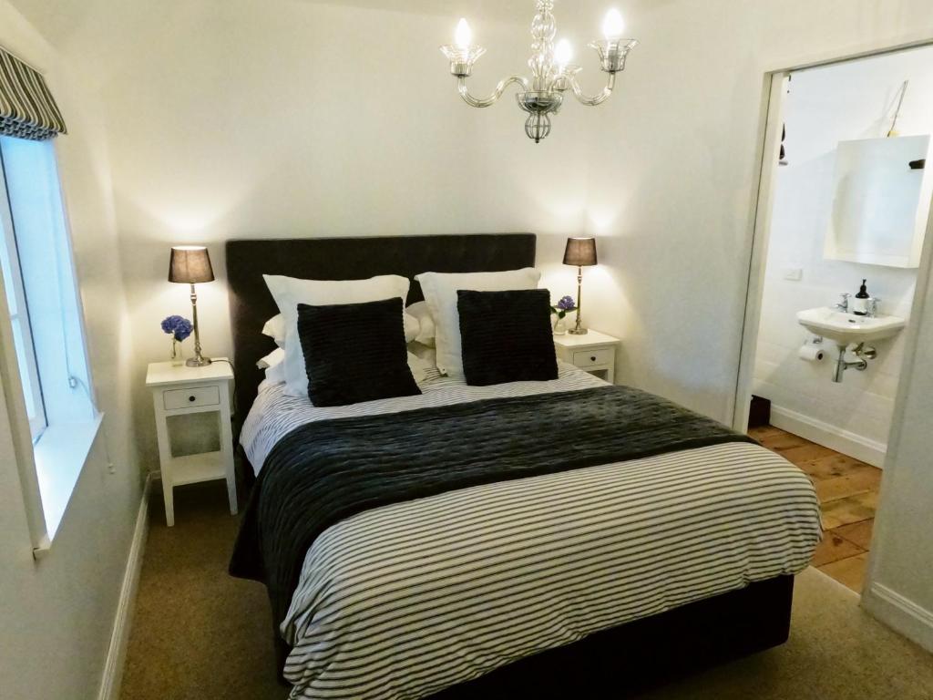 a bedroom with a large bed with two tables and a chandelier at Pinegrove Cottage - Greytown Getaway in Woodside