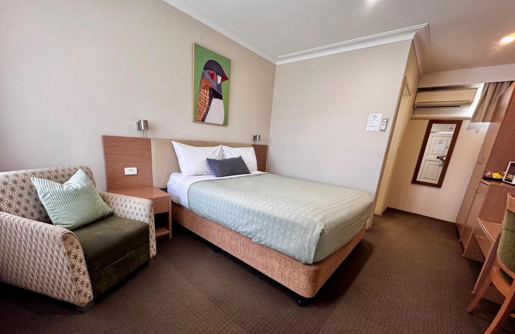 a hotel room with a bed and a chair at Colonial Terrace Motor Inn in Raymond Terrace