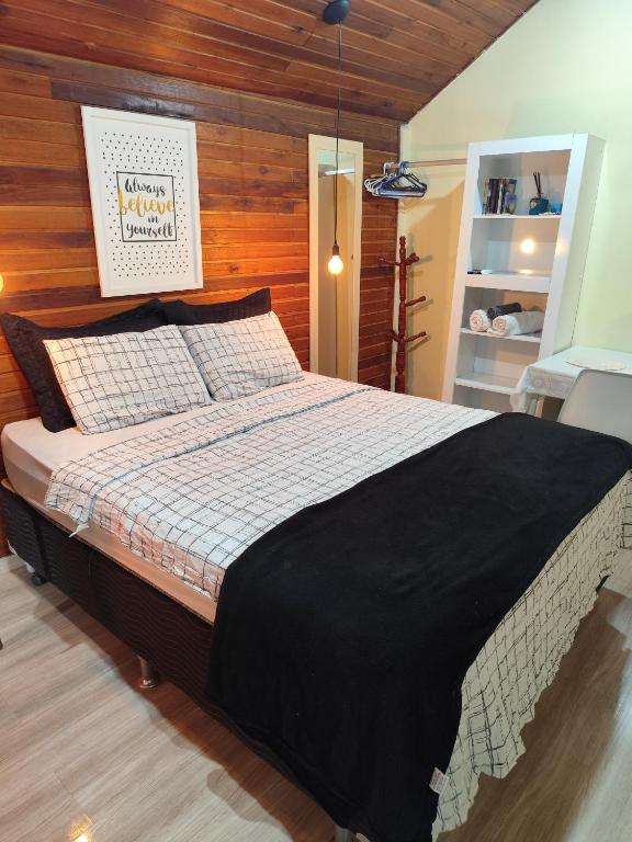 a bedroom with a large bed with a wooden wall at Chalé suíte com ar em Resende in Resende
