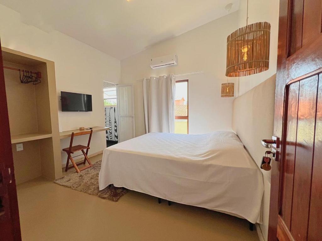 a bedroom with a white bed and a desk at Casa levante in Paracuru