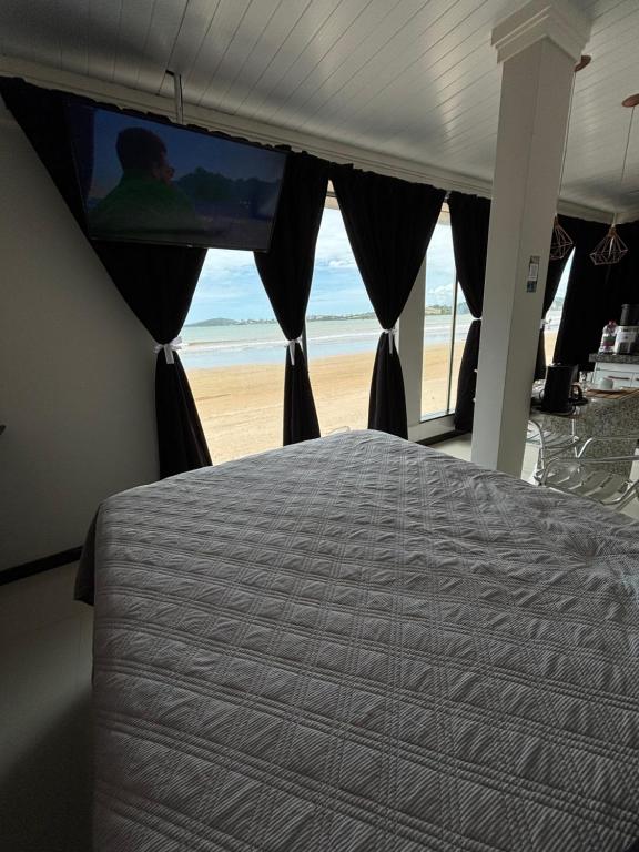 a bedroom with a bed and a view of the beach at Cantinho Sol e Sal in Guarapari