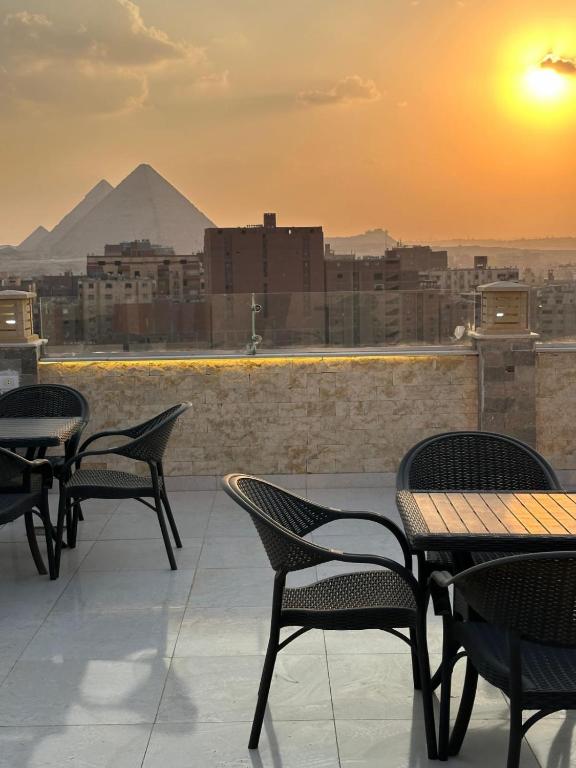 a patio with tables and chairs with a view of the pyramids at sun 3 pyramids view hotel in Cairo