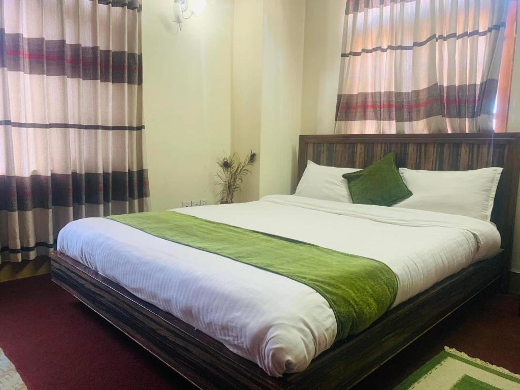 a bedroom with a large bed with white and green sheets at D Eco Resort in Dhulikhel