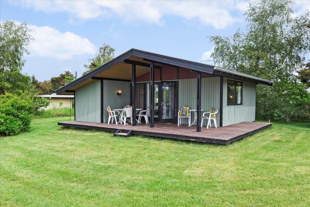 a small green house with a deck and chairs at 1055-Stege-Rylevej-21 in Stege