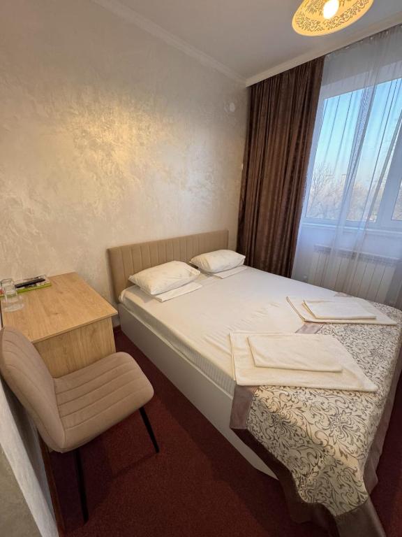 a bedroom with a bed and a chair and a window at TERRA Hotel in Almaty