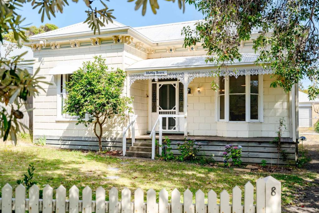 a white house with a white picket fence at Perfect Point Lonsdale Cottage in Point Lonsdale