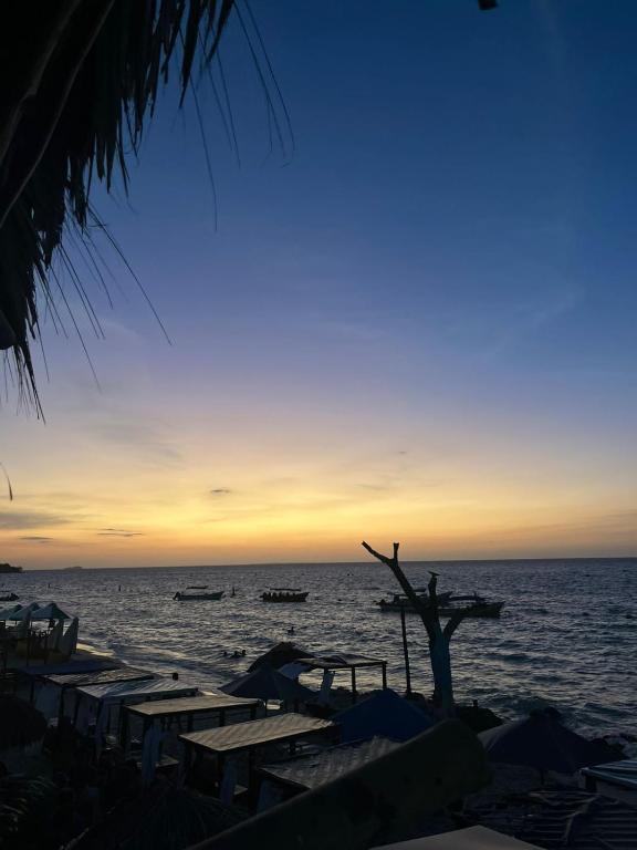 a sunset on the beach with boats in the water at Coco Cabaña Barú in Cartagena de Indias