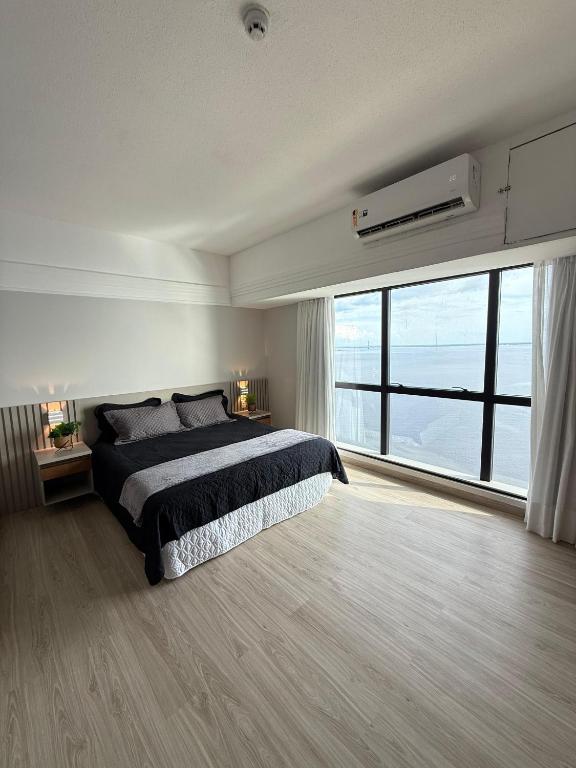 a bedroom with a large bed and a large window at Tropical hotel Suíte Realeza in Manaus