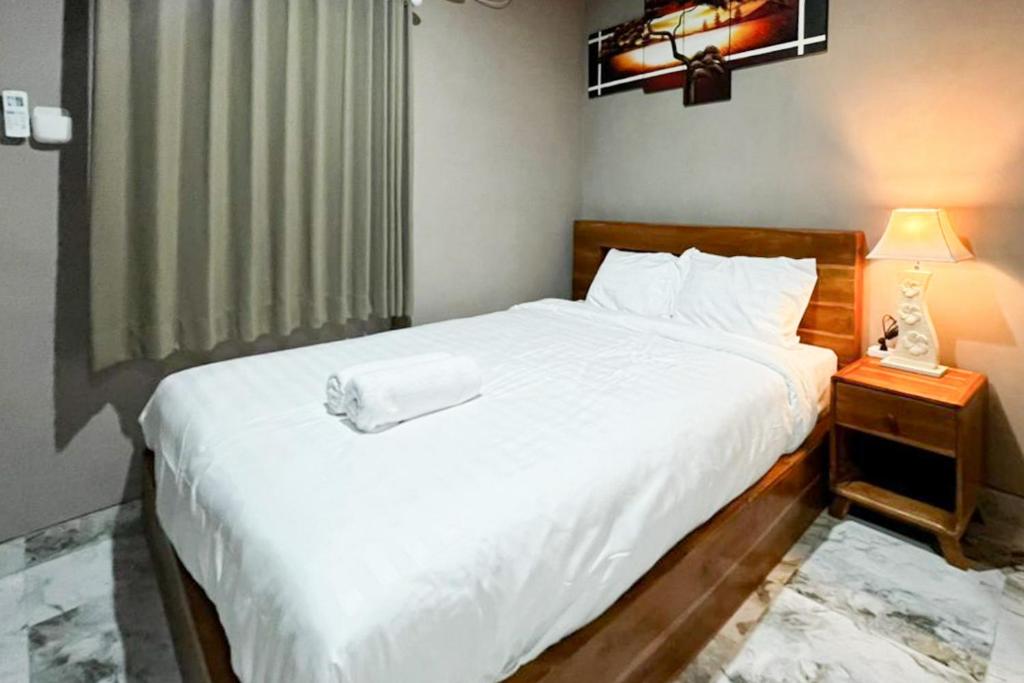 a bedroom with a large white bed with a night stand at Pondok Sagara Mitra RedDoorz in Kapal