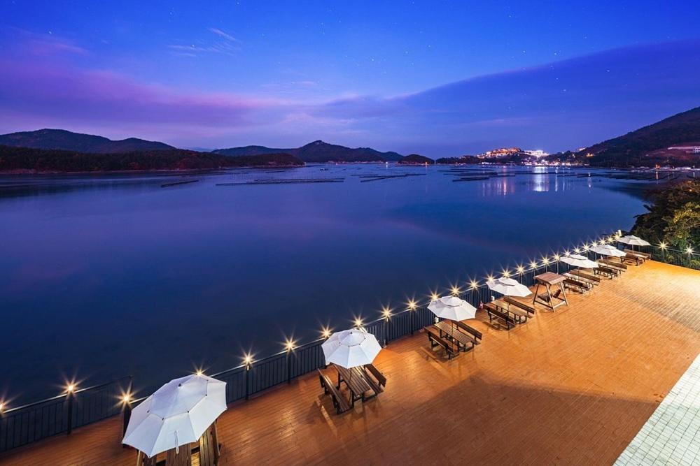 a row of chairs and umbrellas next to the water at Yeosu K-Park Spa Pension in Yeosu