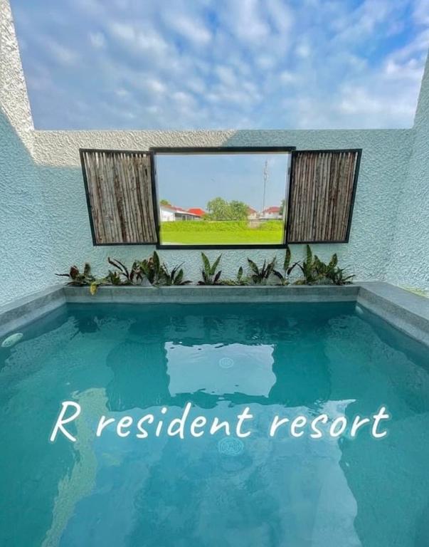 a swimming pool in front of a blue building with a window at R resident resort in Phetchaburi