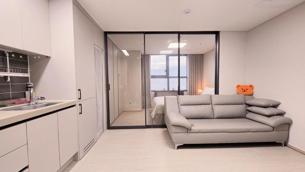a living room with a couch in front of a kitchen at Donghae Eoul Stay in Donghae