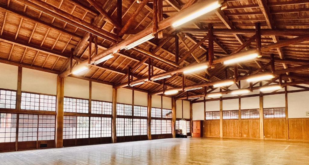 a large room with wooden ceilings and windows at 神庭武道館 in Chichibu