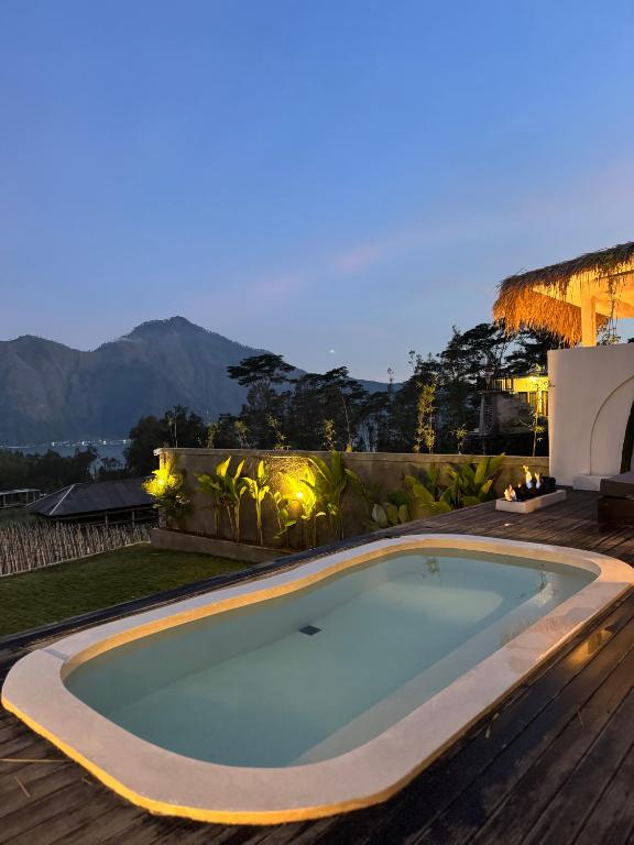 a swimming pool in a backyard with a wooden deck at Aluna Villa Kintamani - Private villa & Hot spring pool in Kubupenlokan