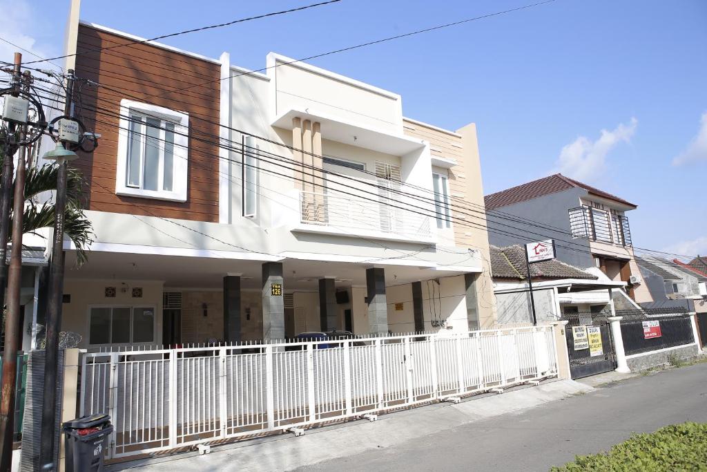 a white house with a white fence on a street at linns house borobudur syariah malang in Blimbing