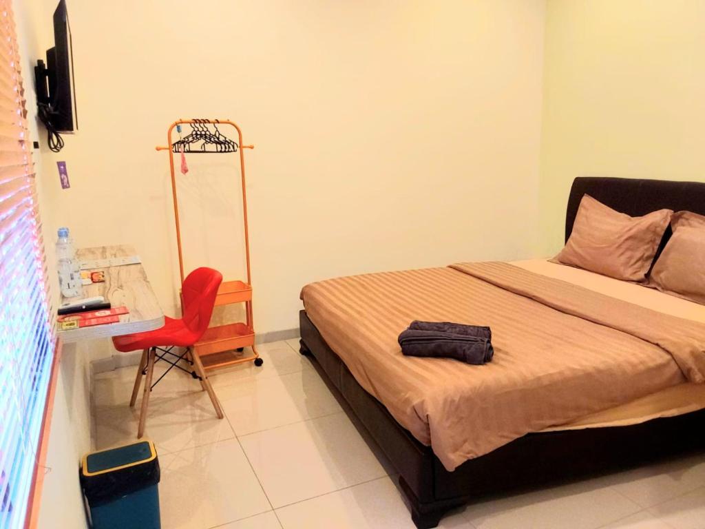 a bedroom with a bed and a red chair at Graha Citra Cirebon in Cirebon