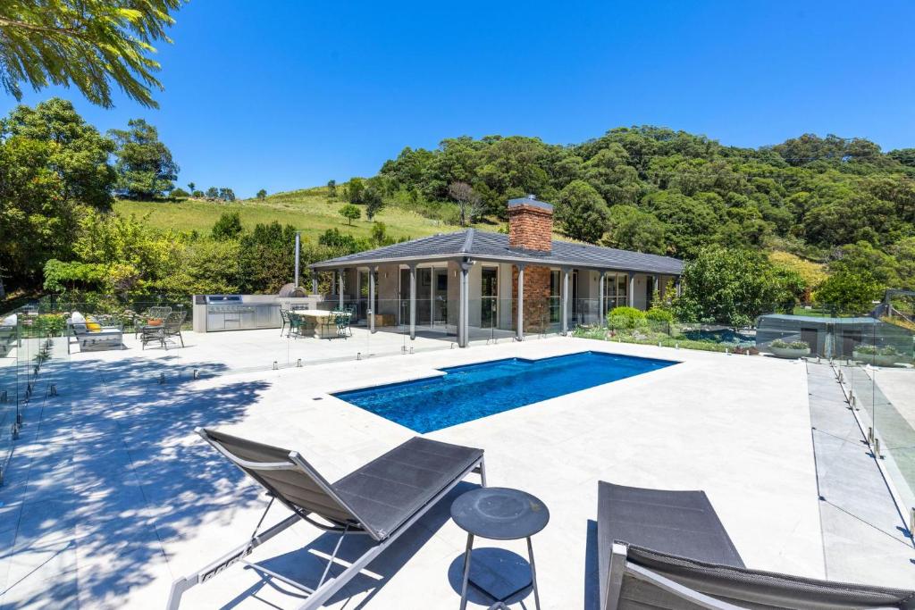 a swimming pool with chairs and a house at Moonraker - Fireplace with Swimming Pool in Broughton Village