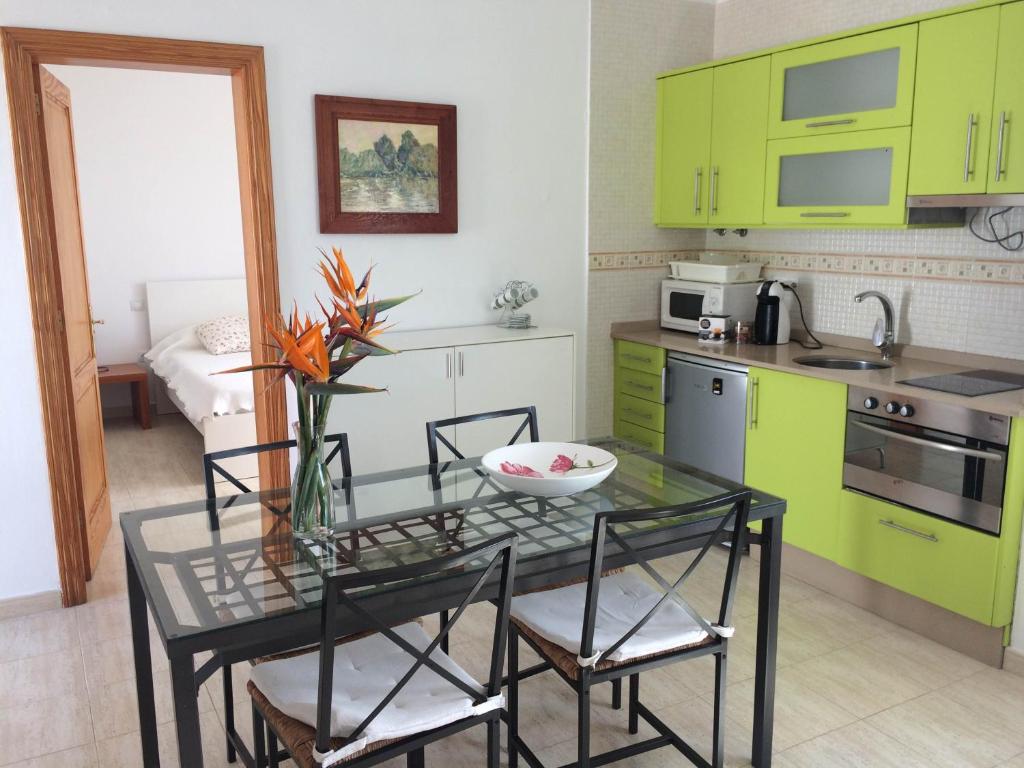 プラヤ・オンダにあるAires de Marのキッチン(緑のキャビネット、ガラステーブル、椅子付)