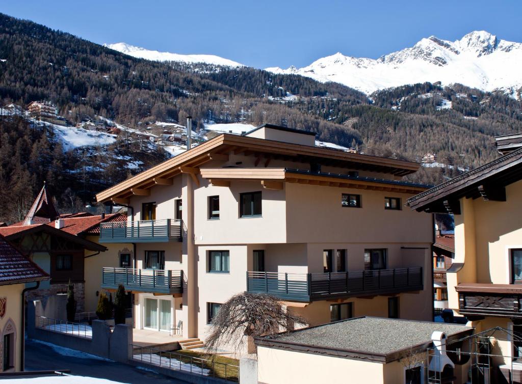 a building with snow covered mountains in the background at Appartment Viertler in Sölden