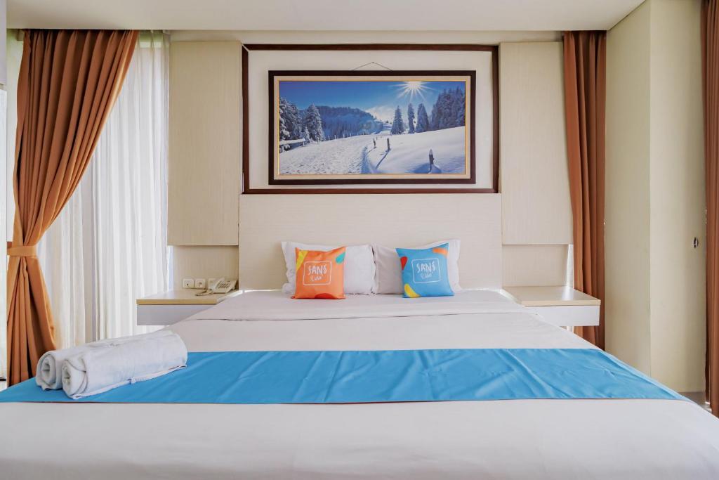 a bedroom with a bed with blue and orange pillows at SANS Vibes Hotel Igloo Cikarang in Cibitung