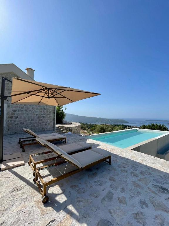 a patio with an umbrella and a swimming pool at Luxury stone house with infinity pool in Herceg-Novi