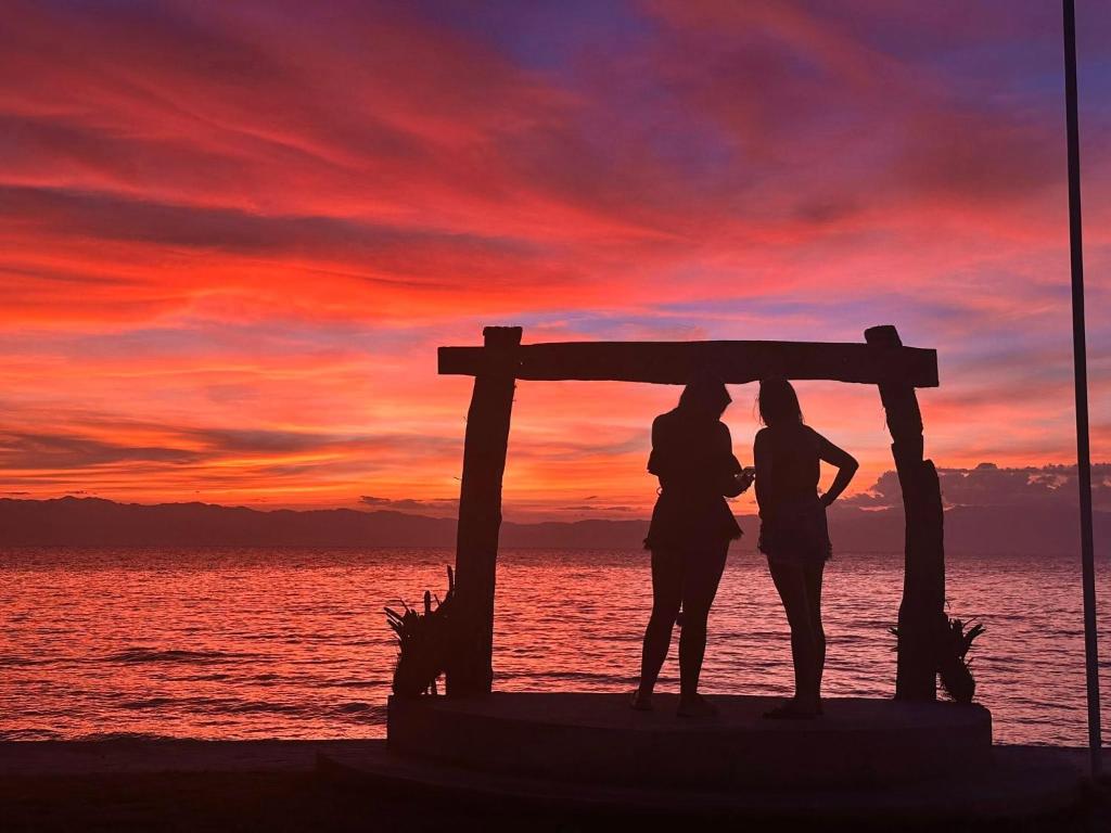 a couple standing under a pergola on the beach at sunset at Rio Beach Resort in Alegria