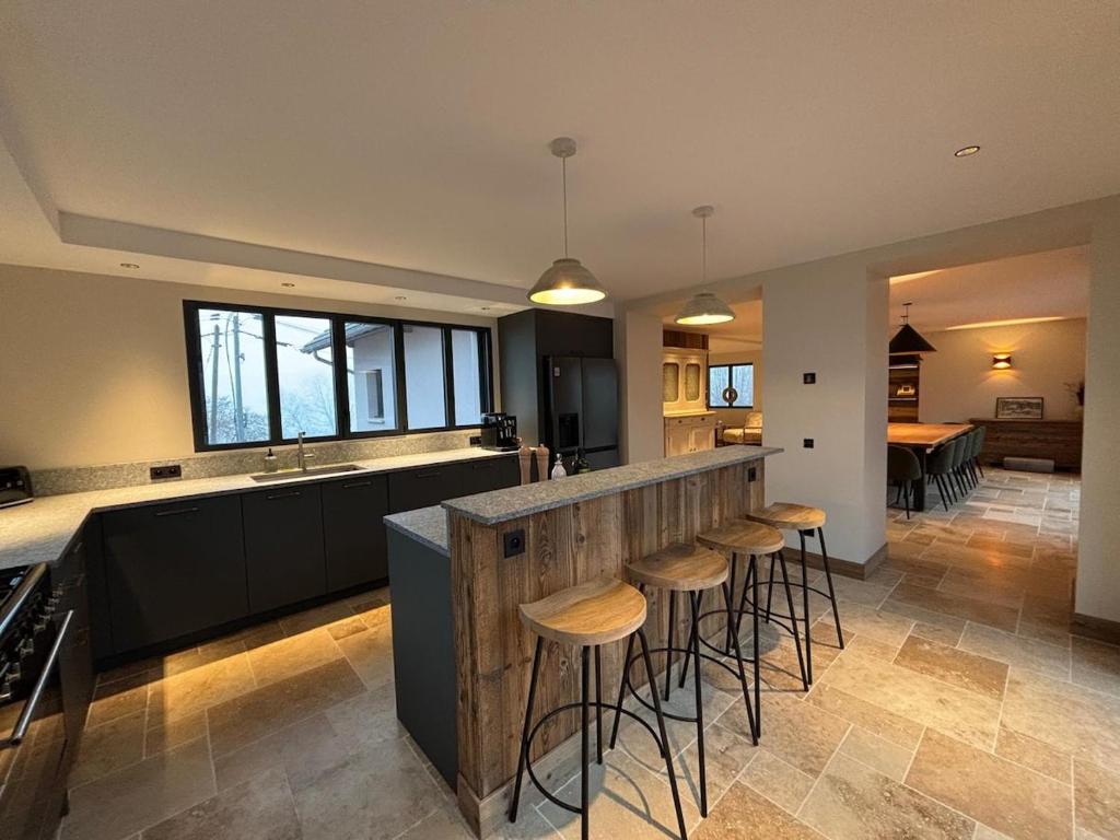 a kitchen with a counter and bar with stools at L'Orée du Peney in Saint-Jean-dʼArvey