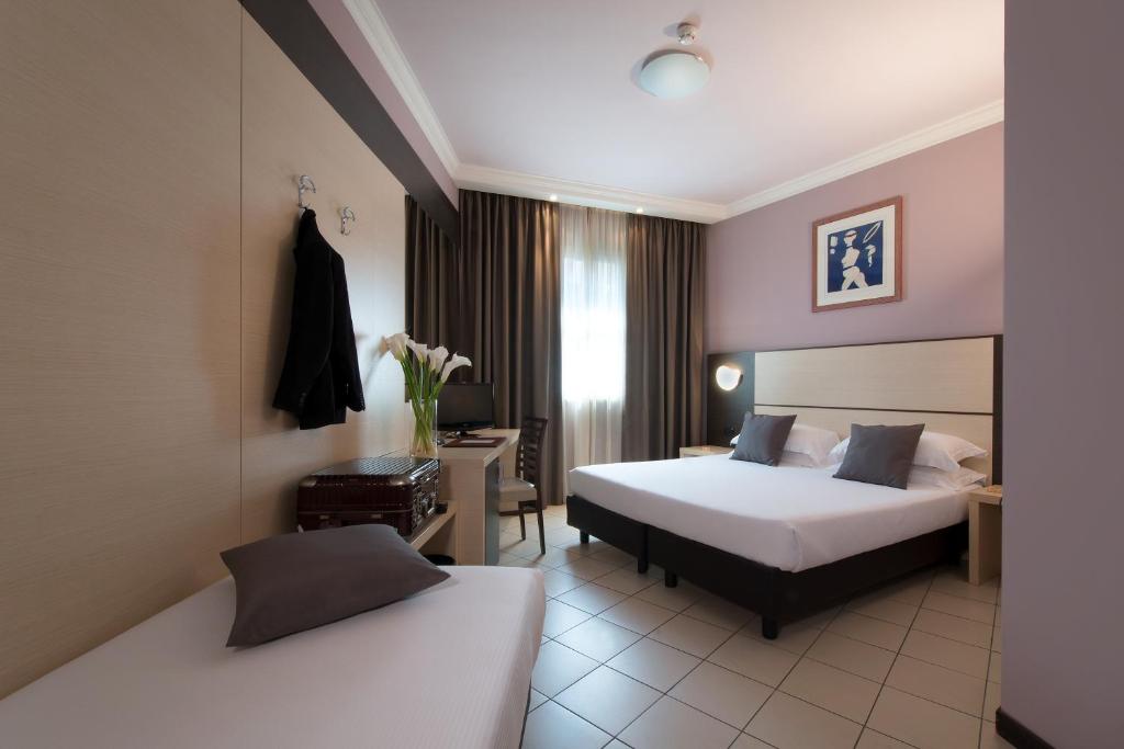 ラ・スペツィアにあるCDH ホテル ラ スペツィアのベッド2台とデスクが備わるホテルルームです。