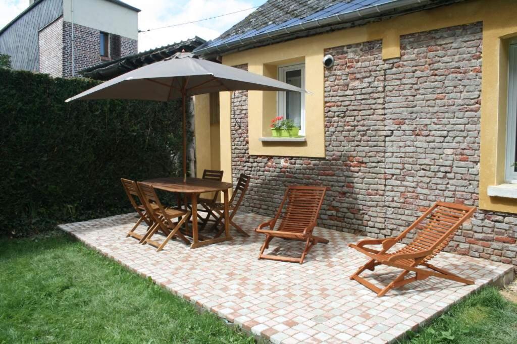 une terrasse avec une table, des chaises et un parasol dans l'établissement Gîte Pays D'Auge Lisieux Centre, à Lisieux