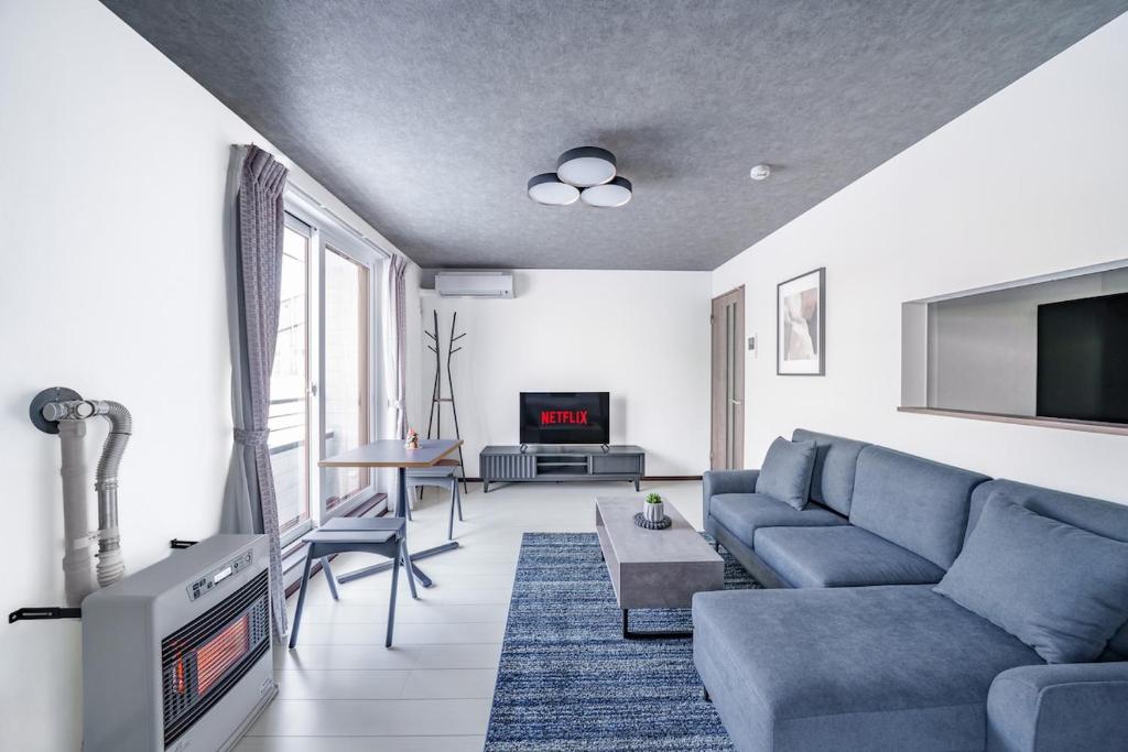 a living room with a blue couch and a tv at Hills Niseko 105 in Niseko
