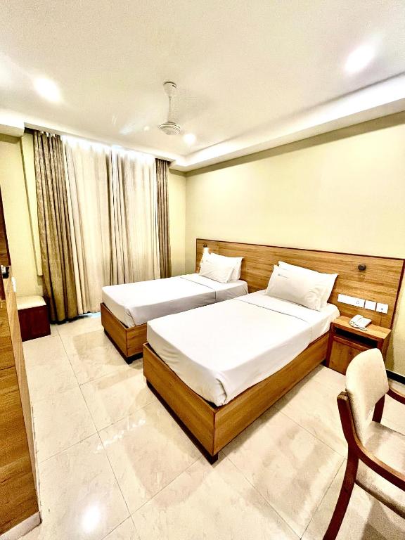 a hotel room with two beds and a chair at Mareena Regency in Cochin
