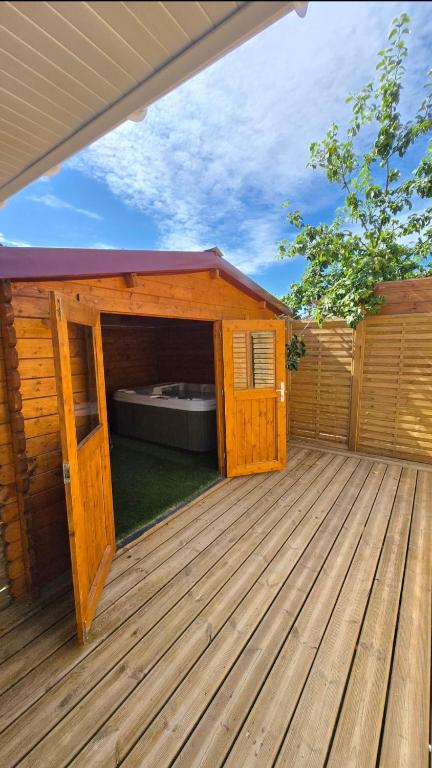 a wooden house with a open door on a deck at Le Gîte de Clément avec Spa privatif in Courset