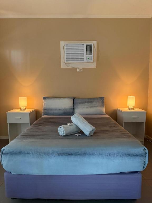 a bed with two pillows and a air conditioner on it at Cadney Park Accommodation in Coober Pedy