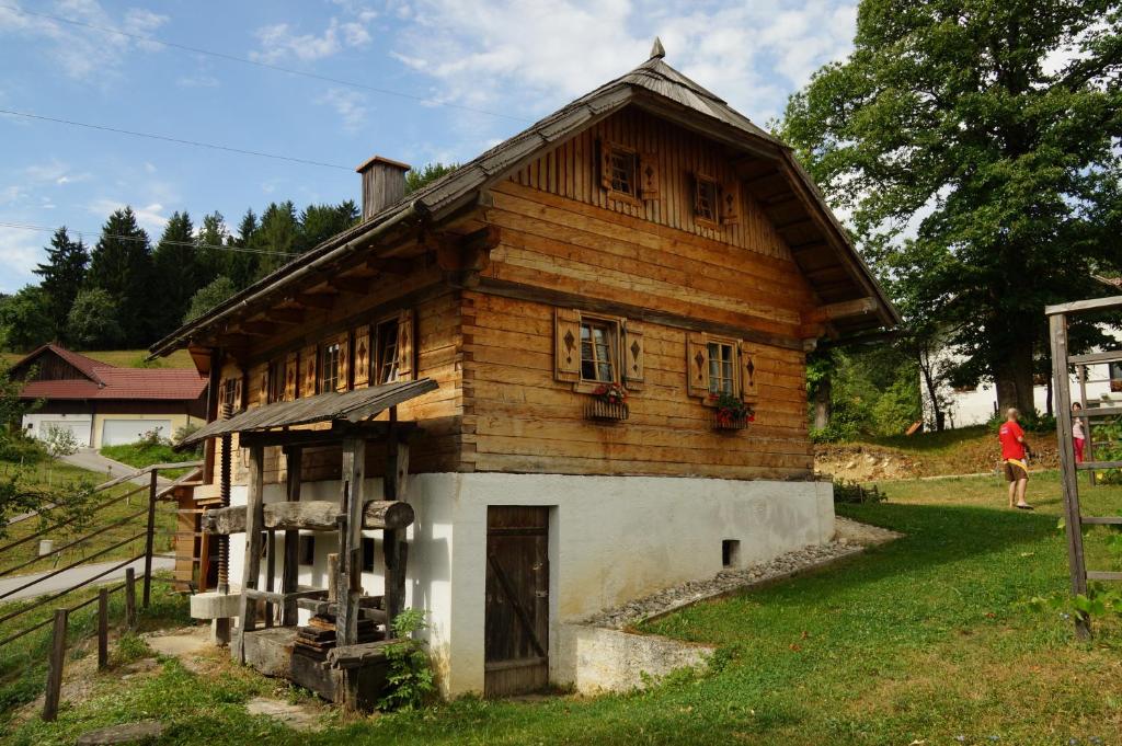 a small wooden house with a woman walking past it at Tourist farm Samec in Sele