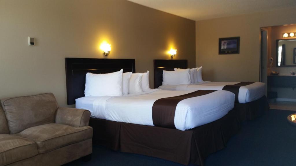 a hotel room with two beds and a chair at Chinook Country Inn in Sundre
