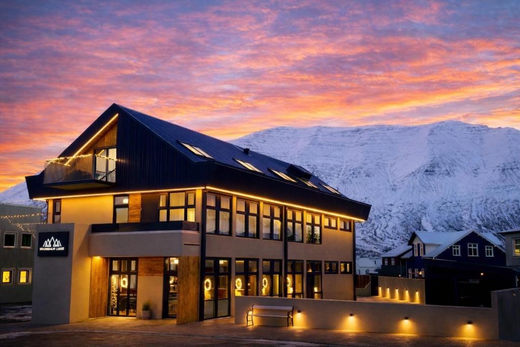 a building at sunset with mountains in the background at Hvanndalir Lodge in Ólafsfjörður