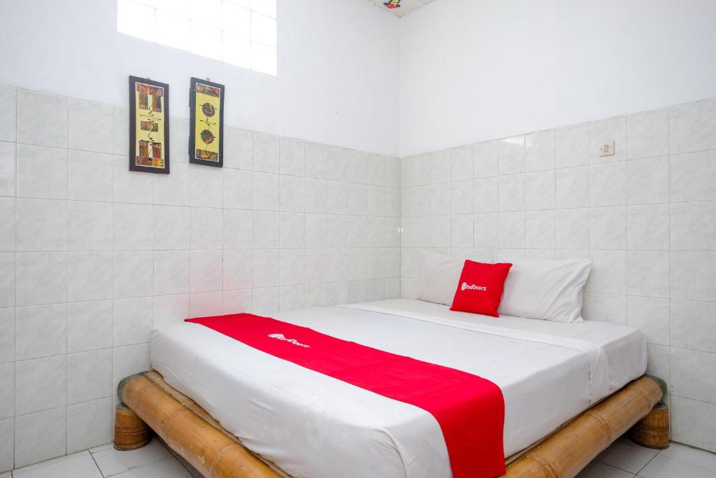 a bed in a room with a red blanket on it at RedDoorz near Jawa Timur Park 1 in Batu