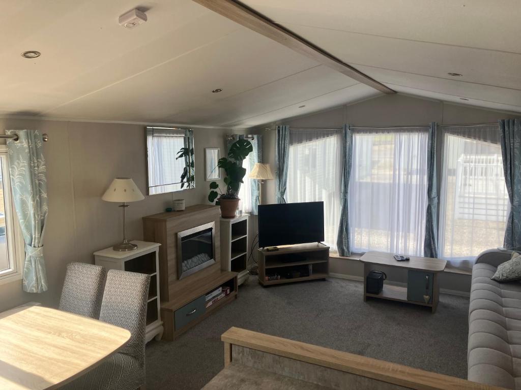 a living room with a tv and some windows at Moray Coast getaway in Lossiemouth