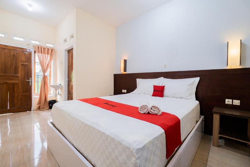 a bedroom with a large bed with slippers on it at RedDoorz at Omahku Guest House Batu in Malang