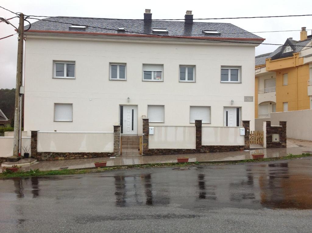 una casa blanca al lado de una calle en Apartamentos Alejandra, en Barreiros