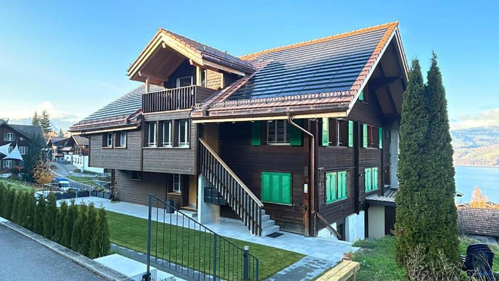 a large wooden house with green doors on it at Apartment Büel in Krattigen in Krattigen