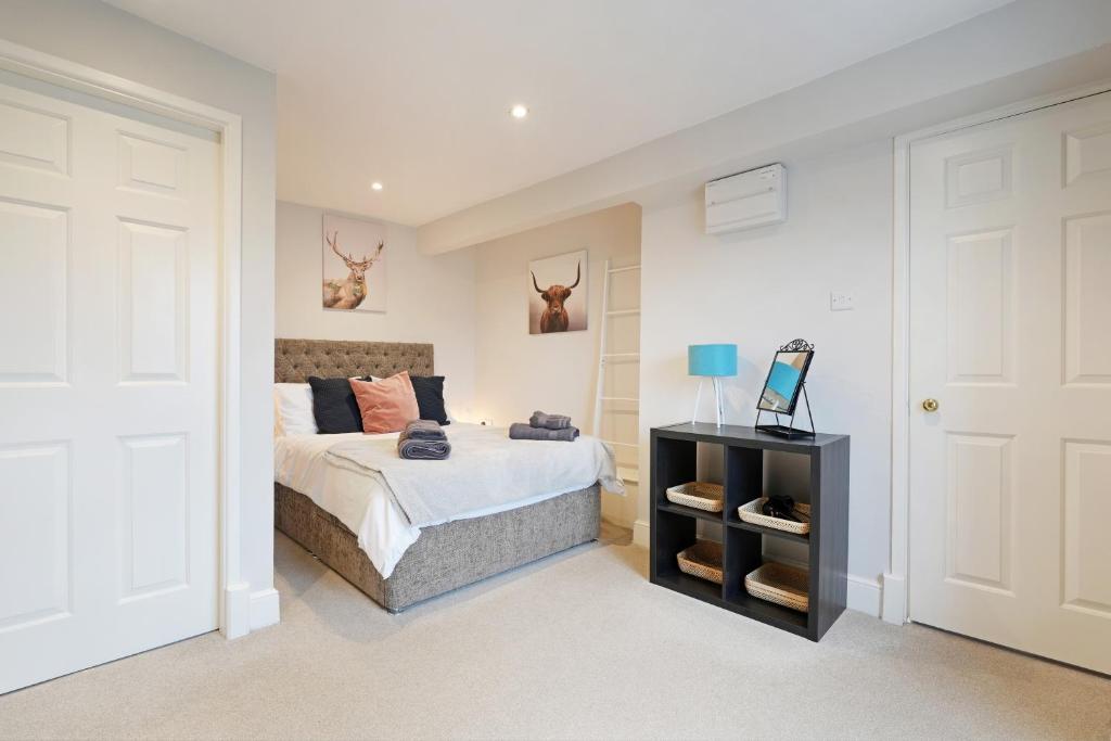 a white bedroom with a bed and a night stand at Stylish Bakewell apartment -walk to cafes and river in Bakewell